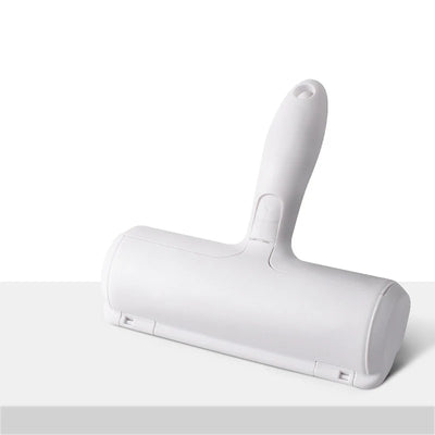 "A white pet hair removal roller with a self-cleaning base, designed for removing cat and dog fur from furniture, carpets, and clothing. The roller features a dual-directional brush and an ergonomic handle for easy use."